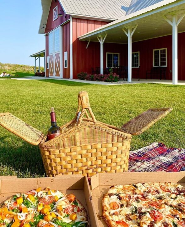 two pizzas and picnic basket outside red barn