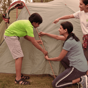 Adult showing kid how to pitch a tent.