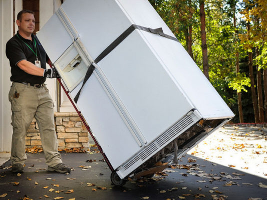 Man moving old refrigerator on a dolly