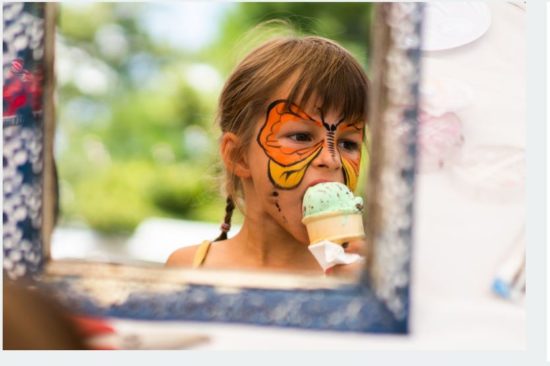 girl with butterfly face paint eating an ice cream cone
