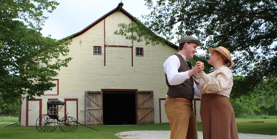 couple in old time clothes outside barn