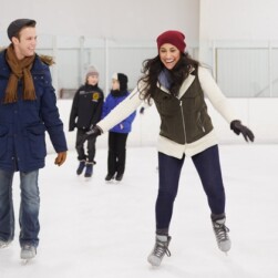 Two adults ice skating at a rink.