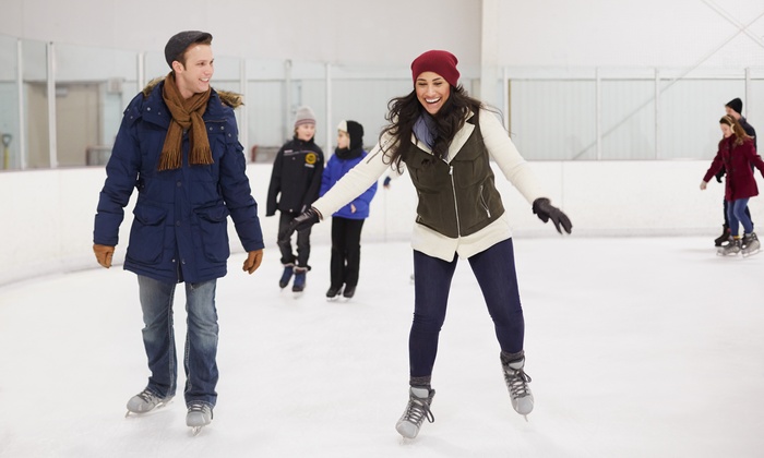 Two adults on an ice skating rink. 
