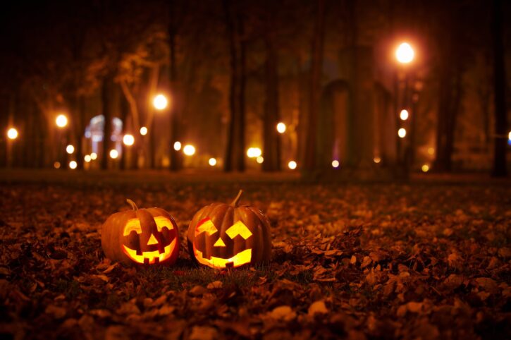 two carved jack-o-lanterns in field at night