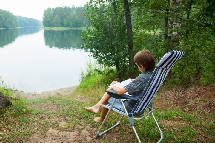 CHILD READING BY MINNESOTA LAKE