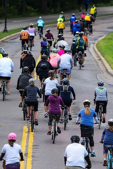 crowd of people on bicycles riding down a street