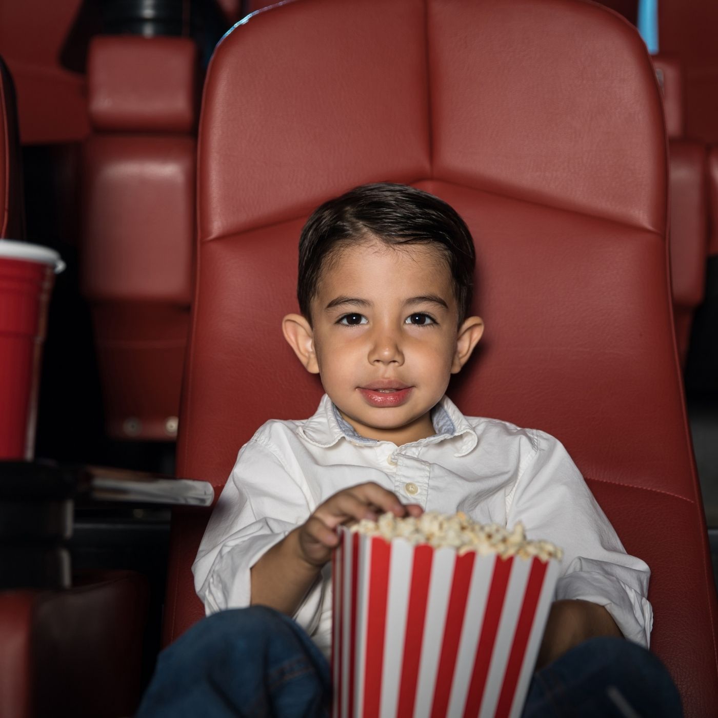little boy in movie theater with popcorn