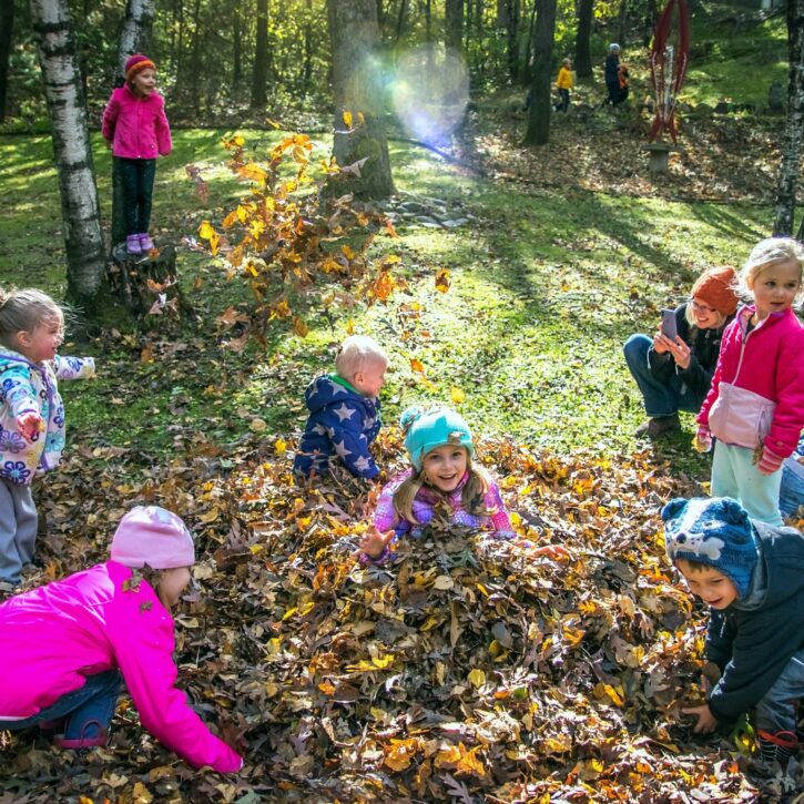 children playing in leaf pile
