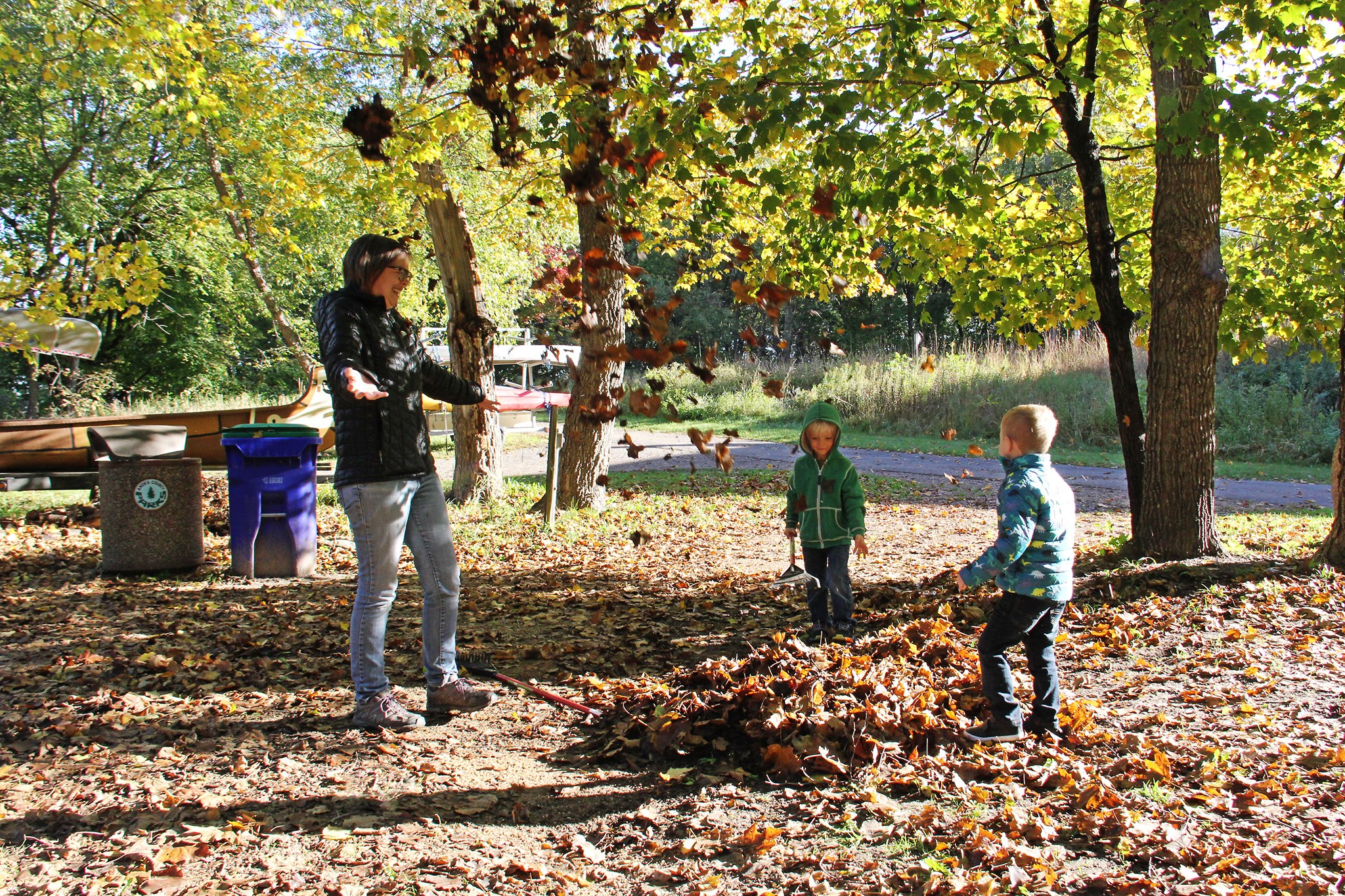 woman and children playing in leaves at Wargo nature center in autumn.