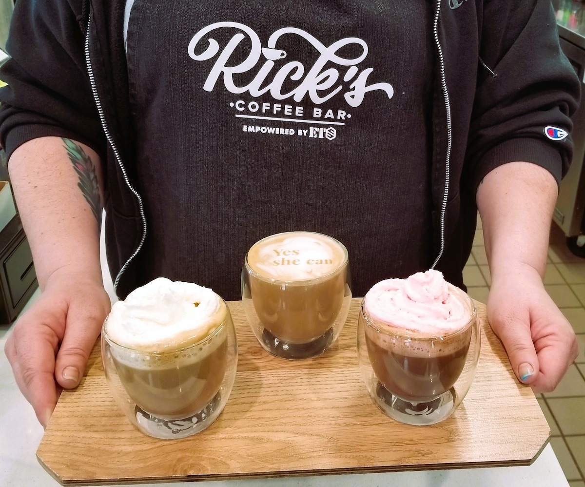 Person holding a Coffee Flight on a wooden board at Rick's Coffee Bar in Minneapolis.