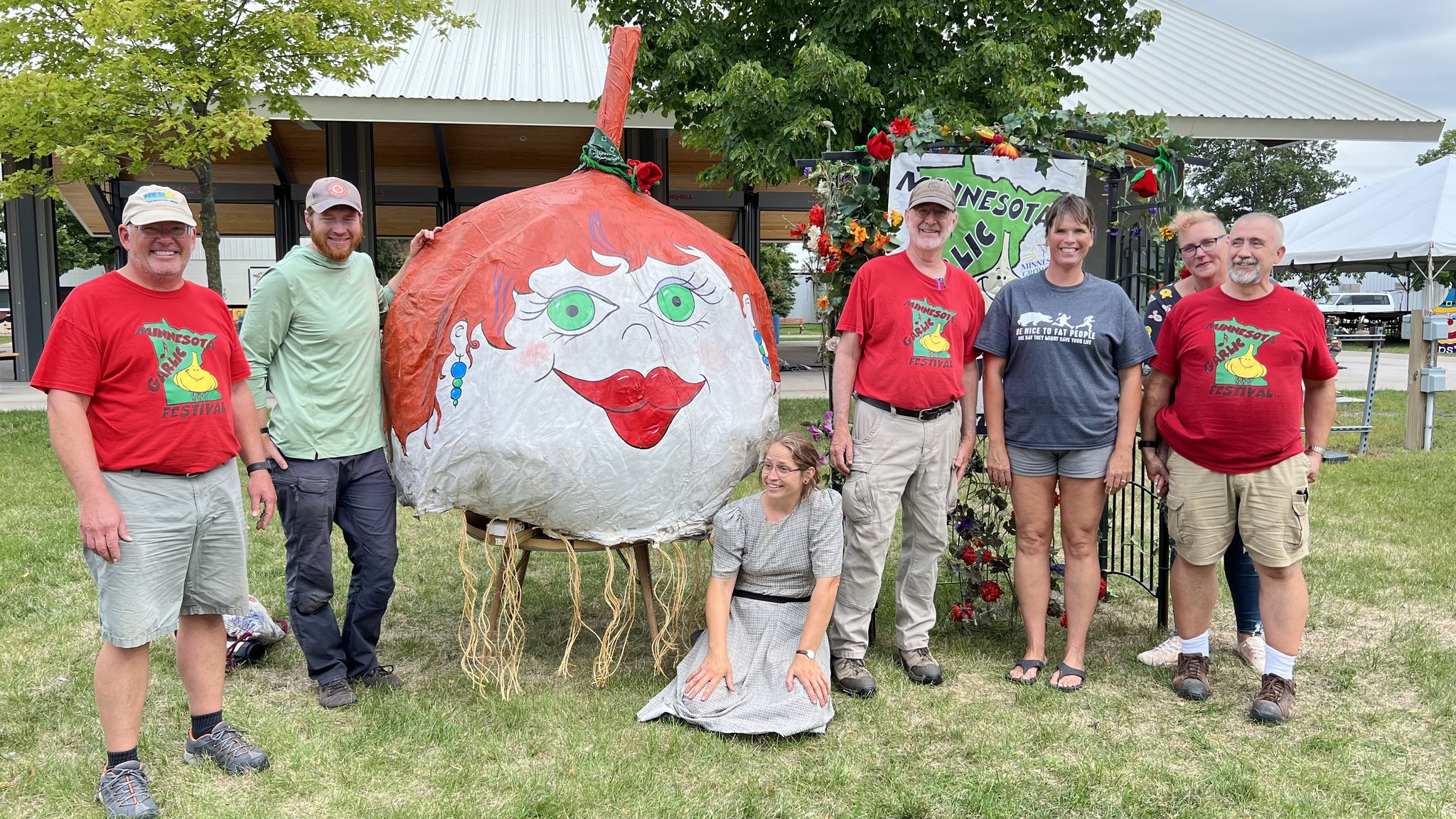People lined up with giant paper mache garlic bulb art at Minnesota Garlic Festival.