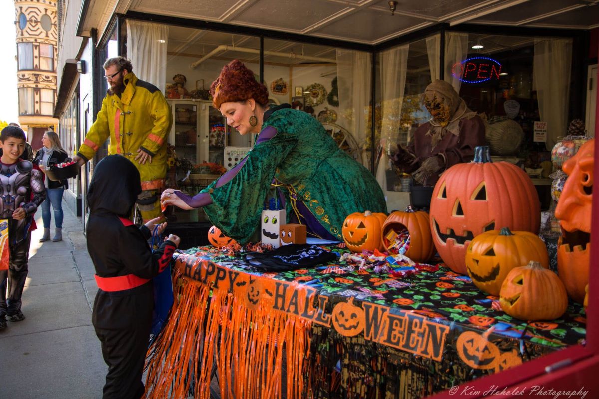 A women vendor giving a child candy for trick or treating.
