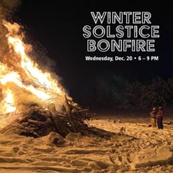 Winter Solstice gigantic bonfire next to two small people.