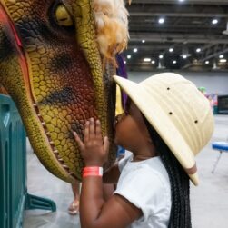 Kid kissing a dino at Jurassic Quest.
