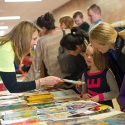 A women helps children select books from a table at the Chanhassen Hooked on Books event.