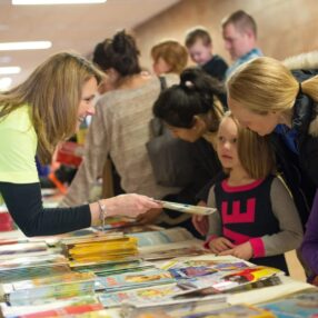 A women helps children select books from a table at the Chanhassen Hooked on Books event.