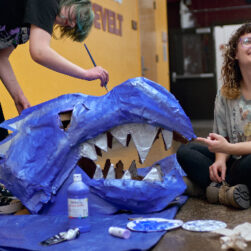Artists creating giant blue dragon puppet head.