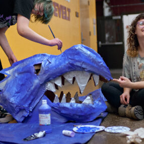 Artists creating giant blue dragon puppet head.