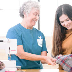 Volunteer helping mend a shirt at a fix it clinic.
