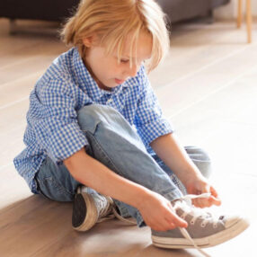 Little boy tying his shoes.