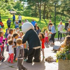 Rosefest mascot with children in a crowd.