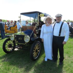 Costumed couple in front of car.