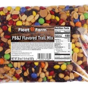 A 20 oz bag of Fleet Farm PB&J Flavored Trail Mix, featuring a mix of peanuts, colorful candy-coated chocolate pieces, raisins, and other ingredients. The package includes a visible nutrition facts label.