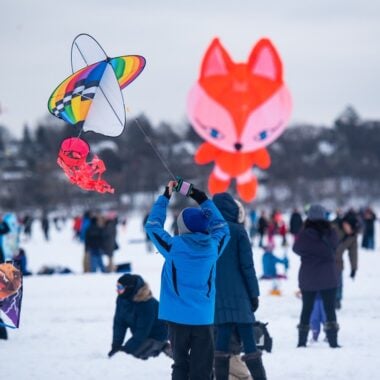 Photo of young boy flying kite and other festivities at the Lake Harriet Kite Festival.