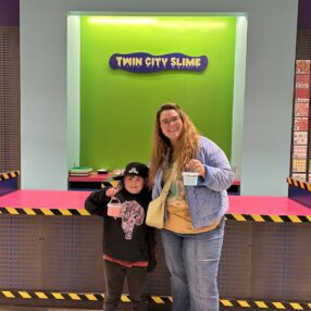 Mom and Son in front of Twin City Slime sign with their custom slimes.