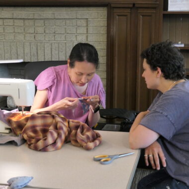 Two people working with a sewing machine to repair clothing.