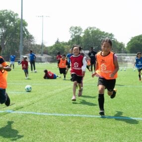 kids playing on field at sanneh foundation summer soccer camp.