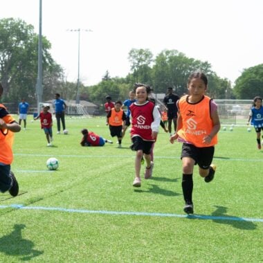 kids playing on field at sanneh foundation summer soccer camp.