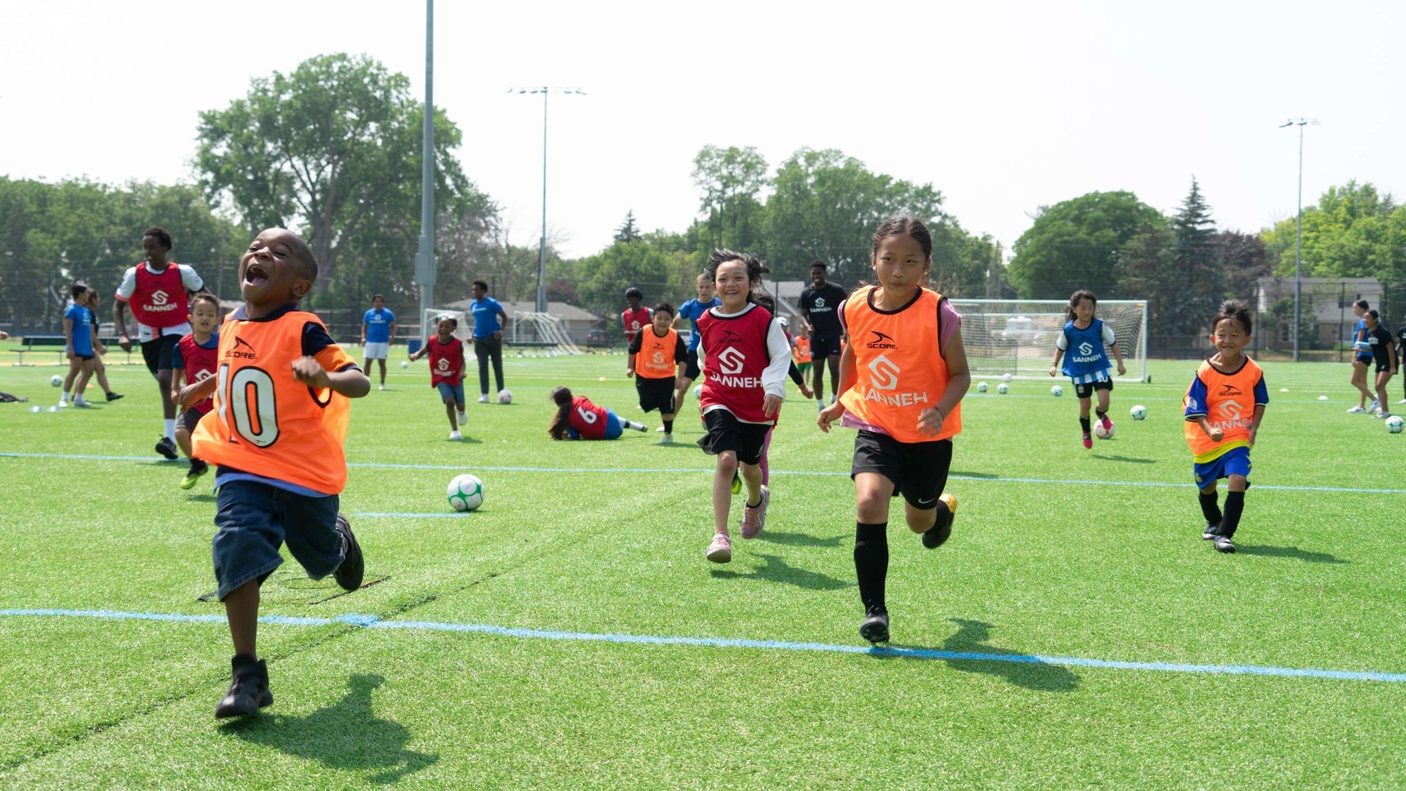 kids playing on field at sanneh foundation summer soccer camp.