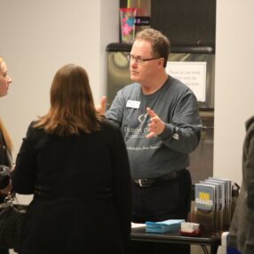 dakota county technical college staff speaking to prospective student and parent at open house event.