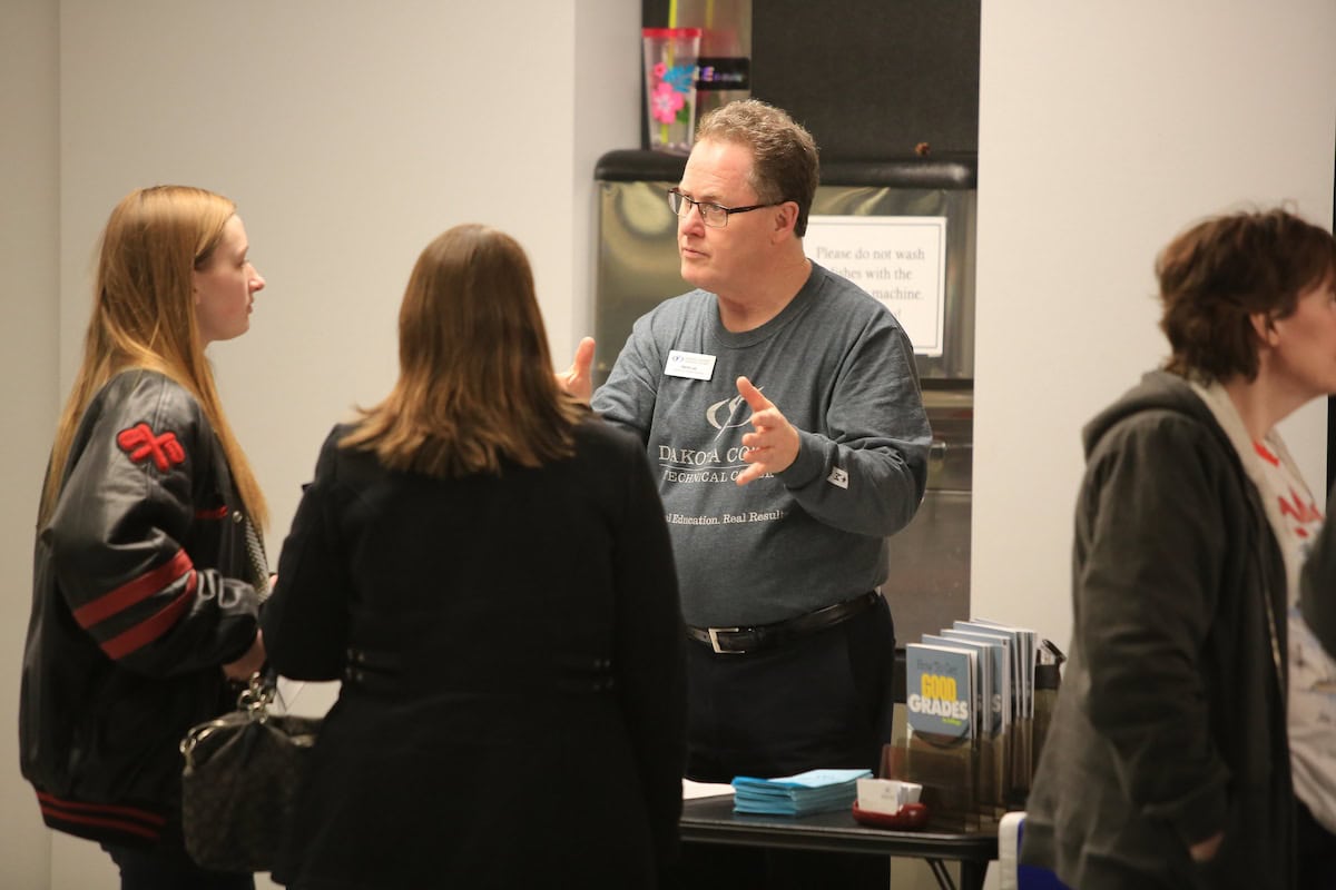 dakota county technical college staff speaking to prospective student and parent at open house event.