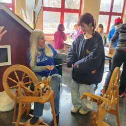 Two women spinning wool into yarn.
