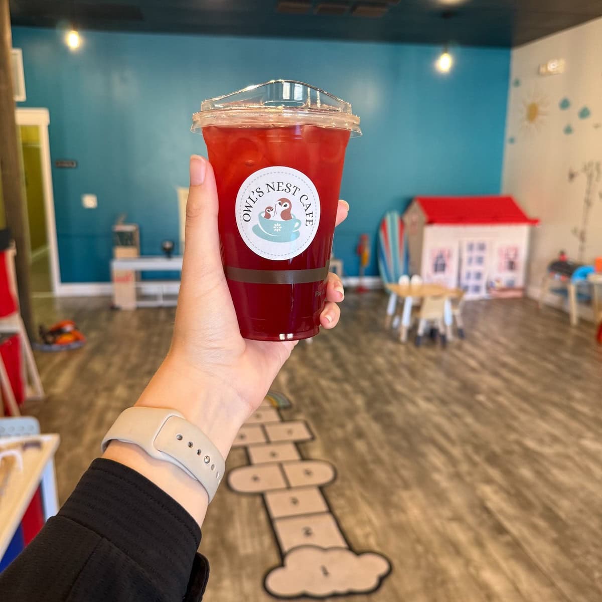 Inside Owl's Nest play area with drink in hand.