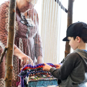 Kid trying the loom at Phipps Community Day.